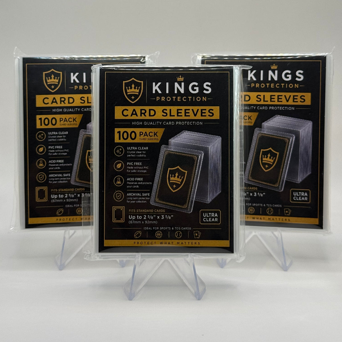 Three packs of Kings Protection card sleeves displayed on clear plastic stands against a white background.