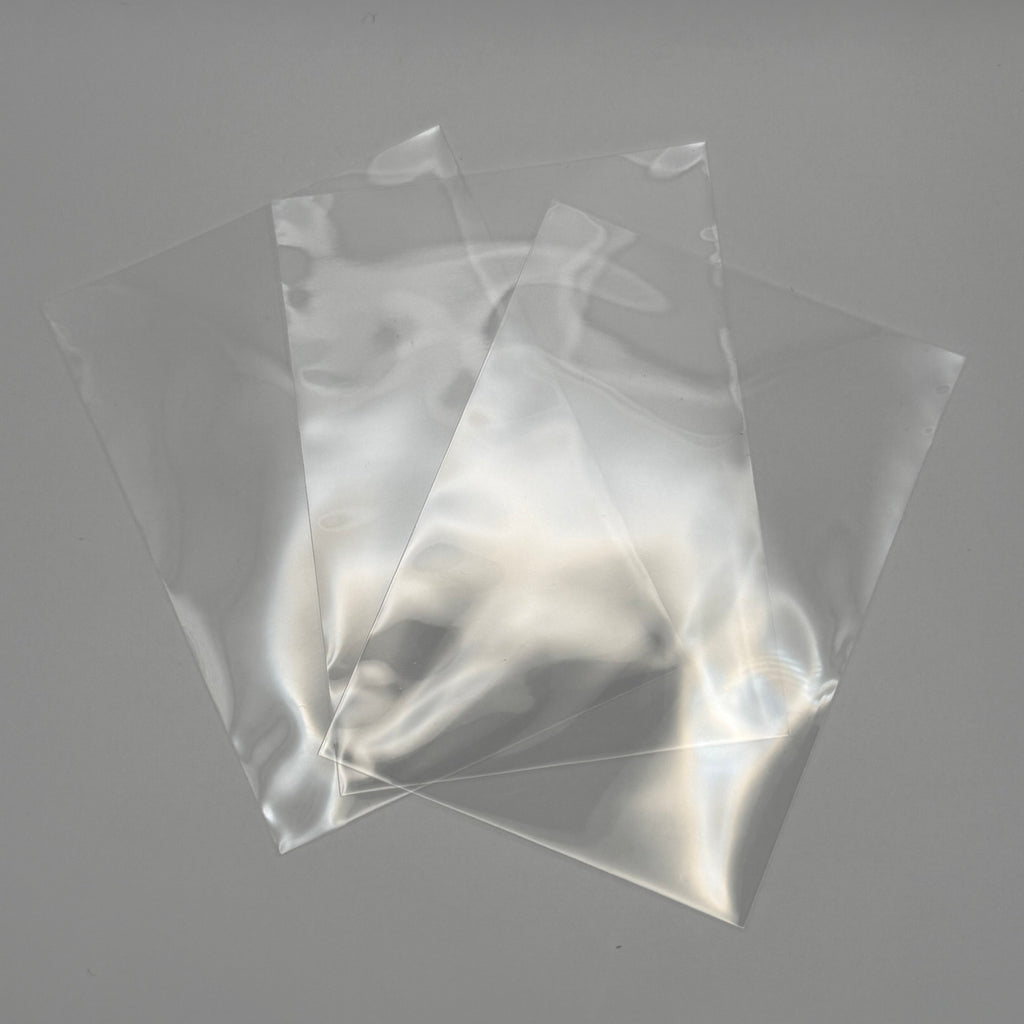 Three clear plastic bags of different sizes arranged in a fan shape on a neutral gray background.