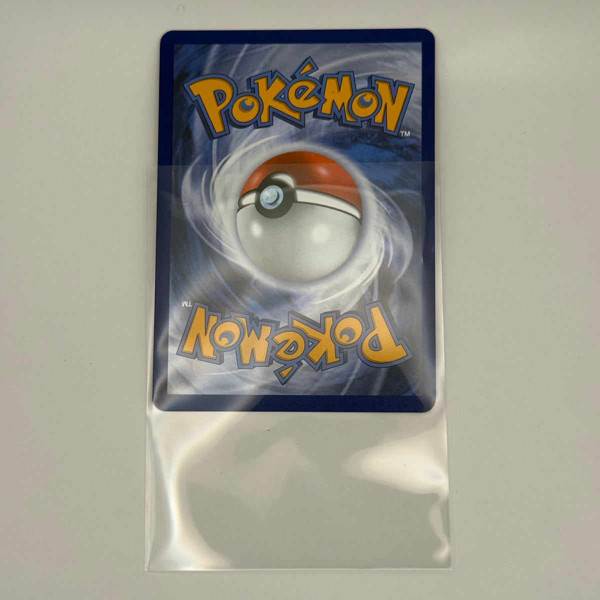 A Pokémon trading card sleeve or protective case with a blue card back featuring the Pokémon logo and a Pokéball graphic, photographed on a plain light background.